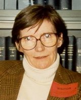 Mary Ross wearing glasses in front of bookcase