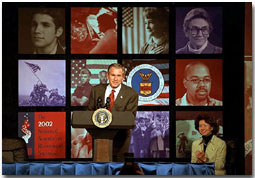 Bush speaking at podium in front of graphic display of photos