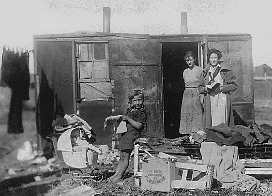 poor mother with children in front of shack