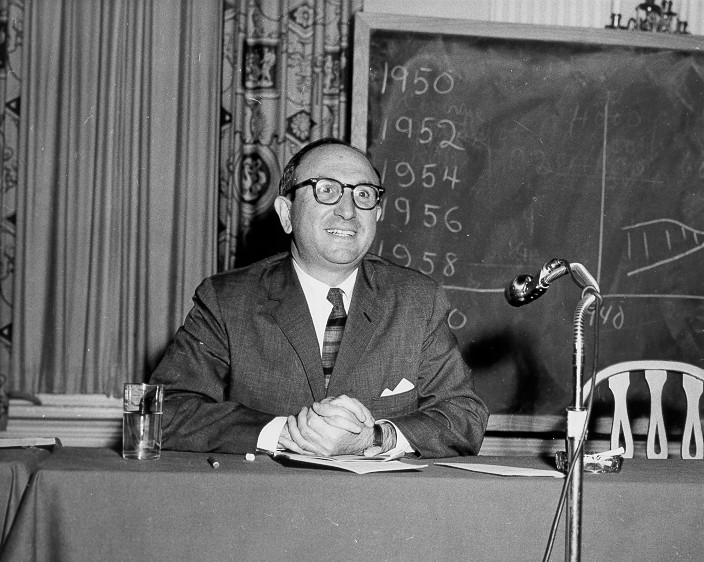 photo of Wilbur Cohen sitting behind table