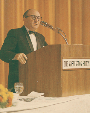 photo of Wilbur Cohen standing behind speaker's rostrum