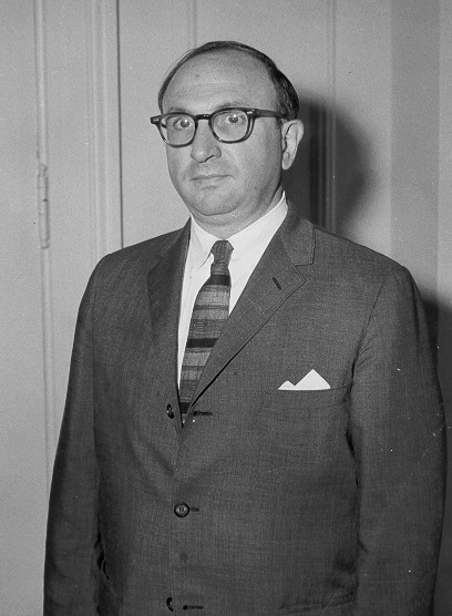 photo of Wilbur Cohen standing against wall