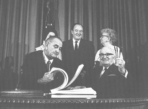 Truman holding up pens Johnson flipping through pages