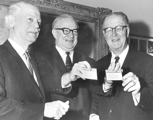 three men in suits holding Medicare cards