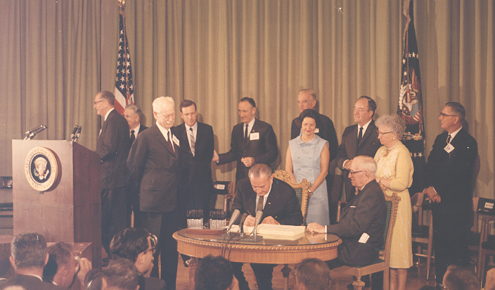 Congressman King looks over LBJ's shoulder as he signs