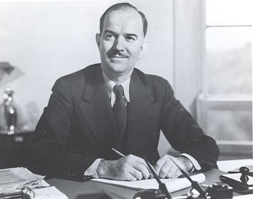 Murray seated at desk signing papers