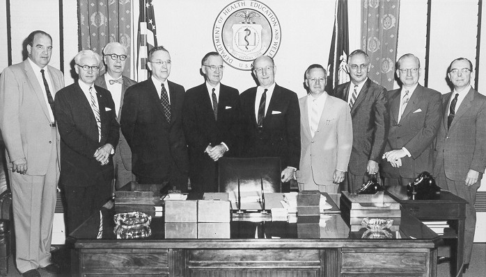 group of men posed behind desk