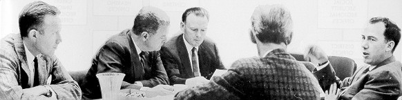 five men sitting around table